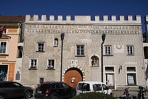 Gmünd, Stadtplatz Nr. 31: Sgrafittohaus, um 1565, über Rundbogenportal Zunftzeichen der Binder