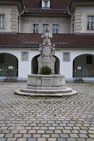 Mauerbach, Kaiser-Jubiläum-Schule, 1908 nach Plänen von Josef Hofbauer errichtet, Kaiser-Jubiläum-Brunnen